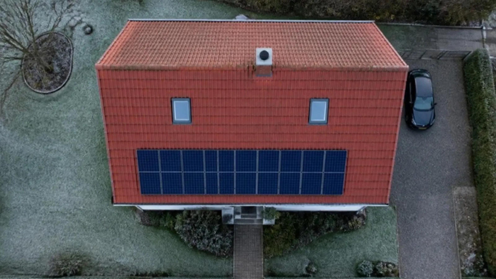 Luftbild eines Einfamilienhauses mit Ziegeldach, Dachfenstern, Kamin und Solaranlage